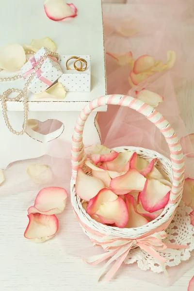 Свадебная корзина с лепестками роз на столе, на светлом фоне — стоковое фото