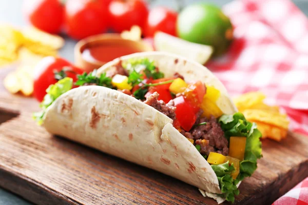 Burrito casero de ternera con verduras, papas fritas en la tabla de cortar, sobre fondo de madera —  Fotos de Stock