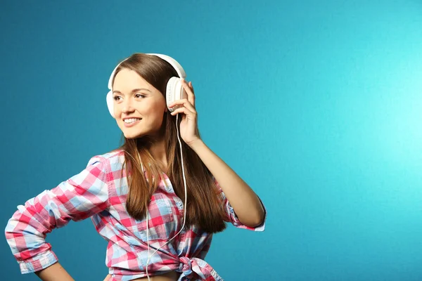 Mladá žena se sluchátky na tyrkysové pozadí — Stock fotografie