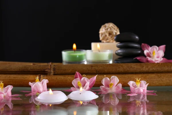 Wellness-Stillleben mit Blumen und Kerzenschein auf schwarzem Hintergrund — Stockfoto