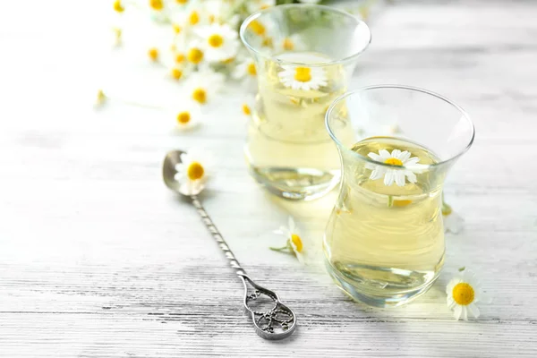 Sklo Heřmánkový čaj s květy heřmánku na barevné dřevěné pozadí — Stock fotografie