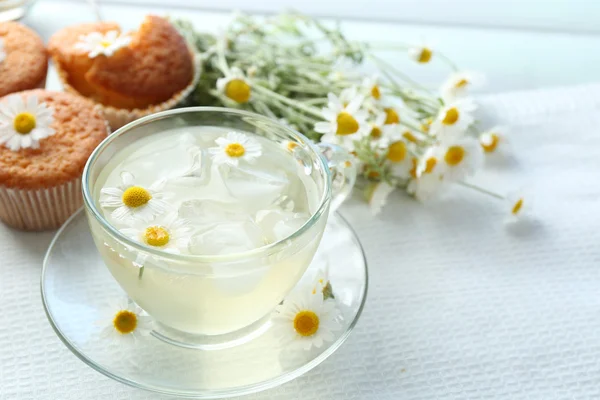 Taza de té de manzanilla con flores de manzanilla y sabrosas magdalenas sobre fondo de madera de color — Foto de Stock