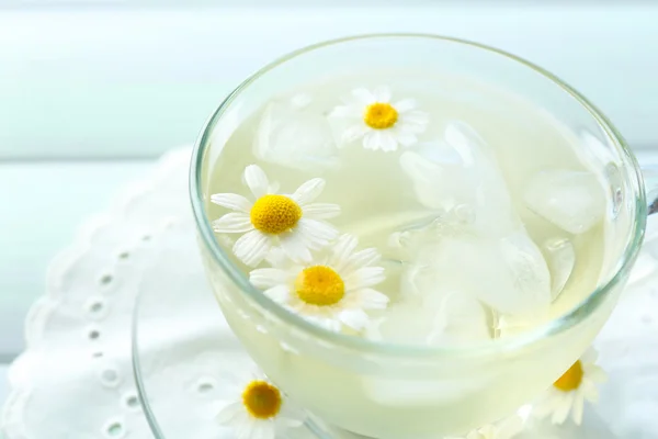 Glas kallt kamomillte med isbitar och kamomillblommor på färg trä bakgrund — Stockfoto