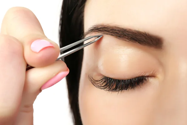 Mujer joven arrancando las cejas con pinzas de cerca —  Fotos de Stock