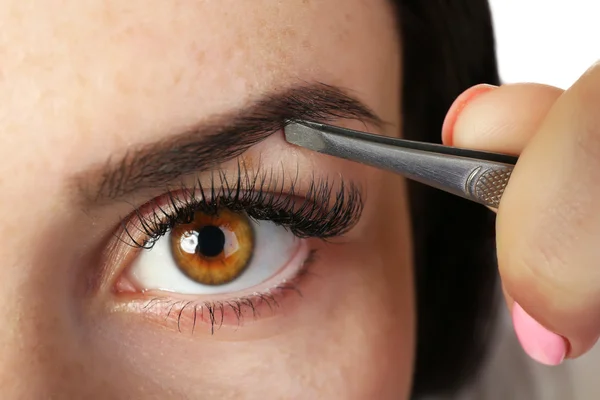 Junge Frau zupft Augenbrauen mit Pinzette aus nächster Nähe — Stockfoto