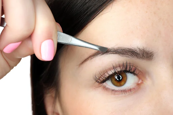 Junge Frau zupft Augenbrauen mit Pinzette aus nächster Nähe — Stockfoto