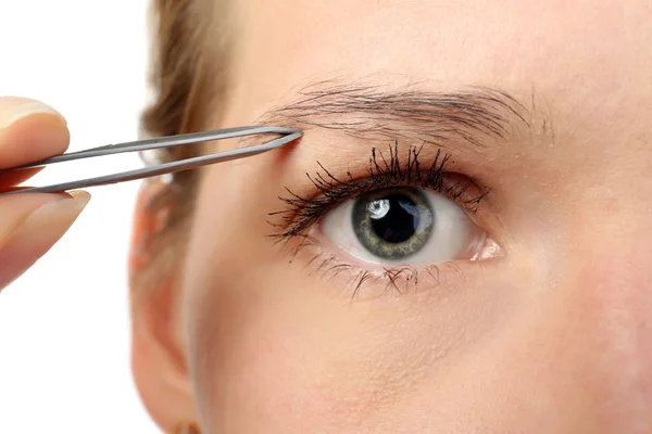 Mujer joven arrancando las cejas con pinzas de cerca —  Fotos de Stock