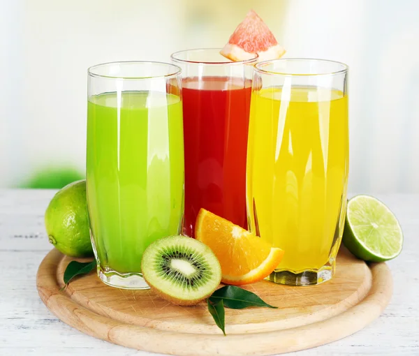 Bicchieri di diverso succo con frutta e menta su sfondo brillante — Foto Stock