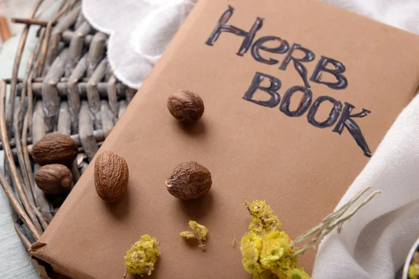 Sušené byliny s muškátovým oříškem a kniha na stole zblízka — Stock fotografie