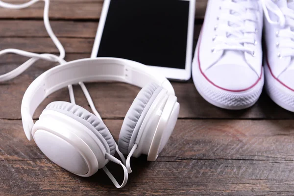 Auriculares con zapatillas y tablet sobre fondo de madera —  Fotos de Stock