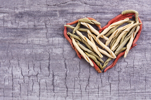 Pasta in heart shape on wooden background