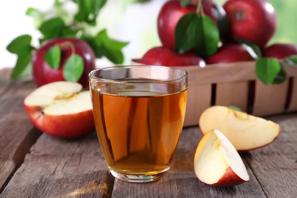 Glass of apple juice with red apples on wooden table, closeup — Stock Photo, Image