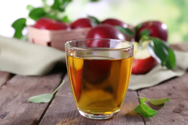 Vaso de zumo de manzana con manzanas rojas sobre mesa de madera, primer plano — Foto de Stock