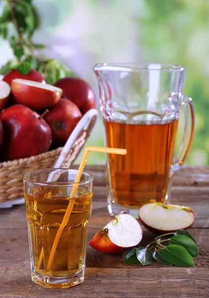 Bicchiere di succo di mela con mele rosse su tavolo di legno su sfondo sfocato — Foto Stock