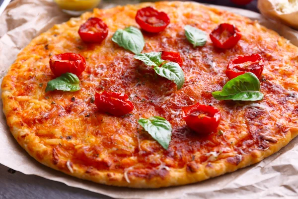 Pizza with basil and cherry tomatoes on parchment, closeup — Stockfoto