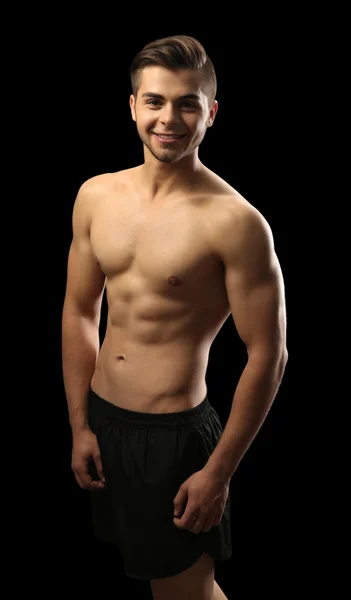 Muskulöser junger Mann mit dunklem Hintergrund — Stockfoto