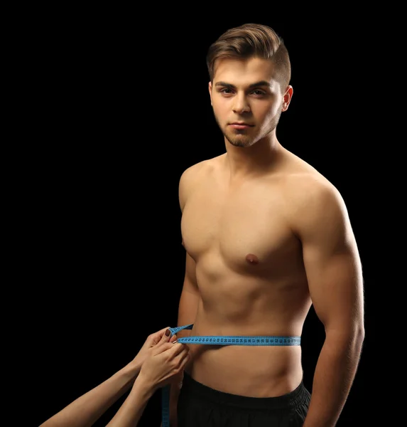 Female hand measuring male muscular on dark background — Stock Photo, Image