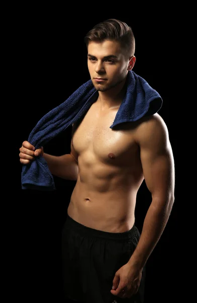 Muscle young man holding towel on dark background — Stock Photo, Image