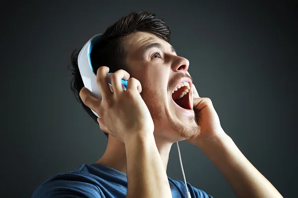 Handsome young man listening to music on  dark background Stock Photo
