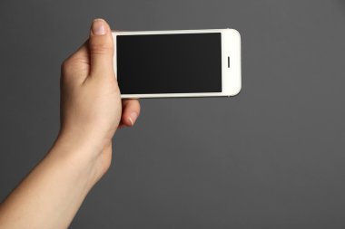 Mobil akıllı telefon gri arka plan üzerinde tutan el
