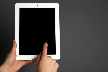 Tablet gri arka plan üzerinde tutan eller