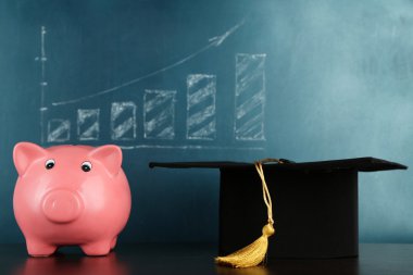 Kumbara blackboard arka plan üzerinde grad şapkalı