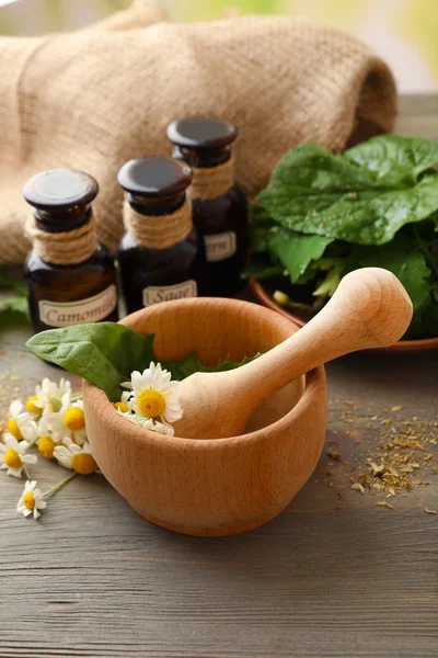 Ervas, bagas e flores com argamassa, sobre fundo de mesa de madeira — Fotografia de Stock