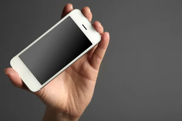 Рука держит мобильный смартфон на сером фоне — стоковое фото