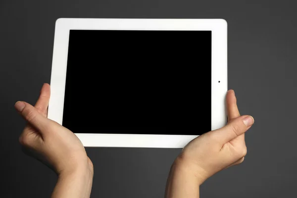 Mãos segurando tablet no fundo cinza — Fotografia de Stock