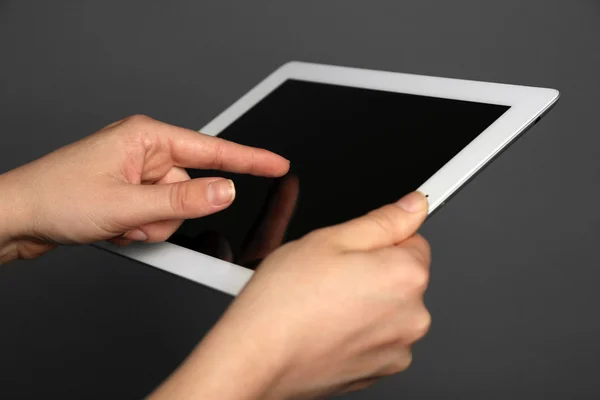 Hands holding tablet on gray background — Stock Photo, Image