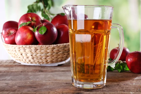 Full jug of apple juice and fruits on bright background — Stock Photo, Image