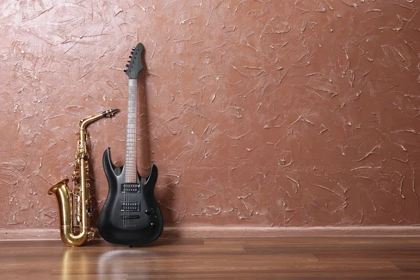 Chitarra elettrica e sassofono su sfondo parete marrone — Foto Stock
