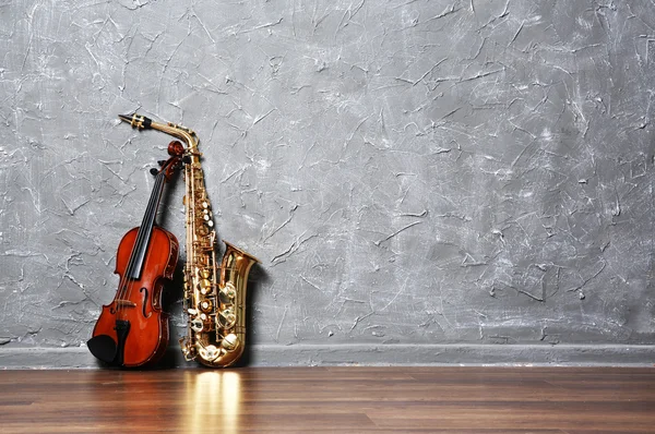 Violin and saxophone on gray wall background — Stock Photo, Image