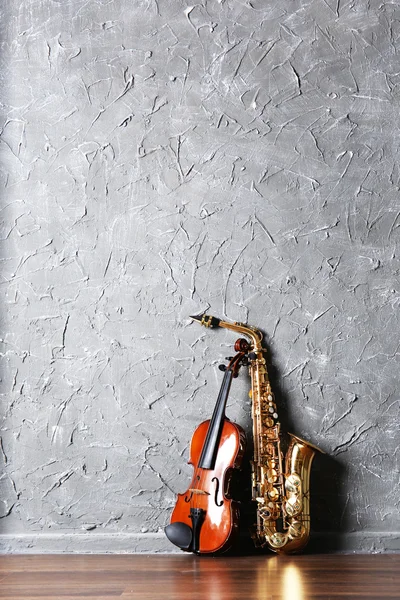 Violino e saxofone no fundo da parede cinza — Fotografia de Stock