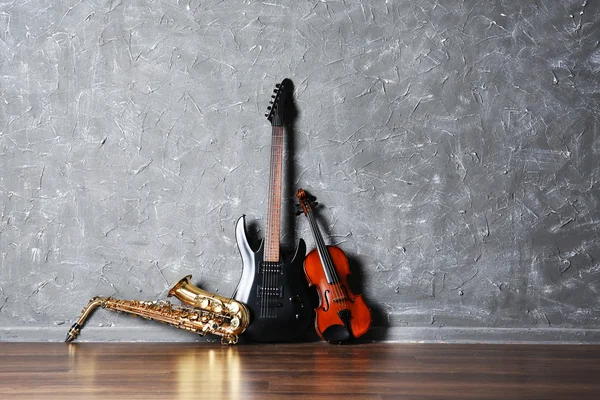 Guitarra eléctrica, saxofón y violín sobre fondo de pared gris —  Fotos de Stock