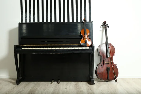 Piano, violoncelo e violino no fundo da parede branca — Fotografia de Stock