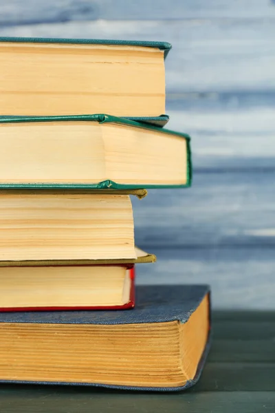 Montón de libros sobre mesa de madera sobre fondo de pared de madera azul — Foto de Stock