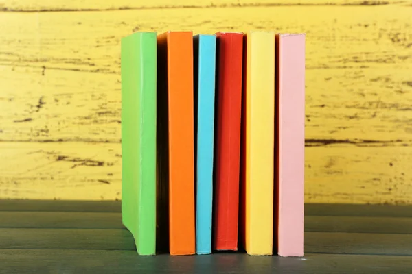 Trave böcker på träbord på gula trävägg bakgrund — Stockfoto
