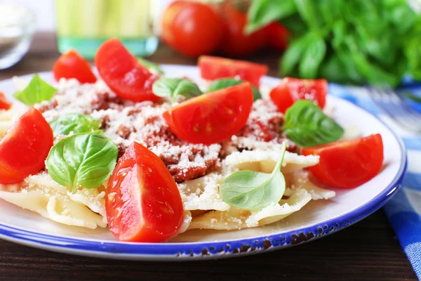 Pasta bolognese with cherry tomatoes in white plate on wooden table, closeup — Stock Photo, Image