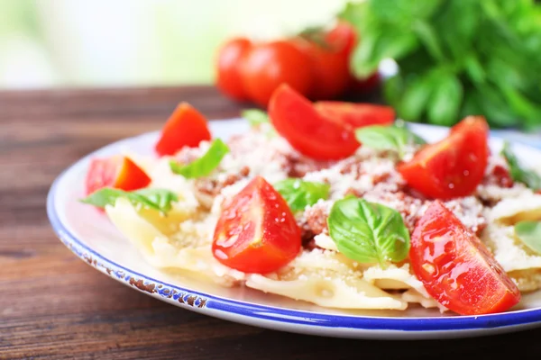 Pâtes bolognaise aux tomates cerises en assiette blanche sur table en bois, gros plan — Photo