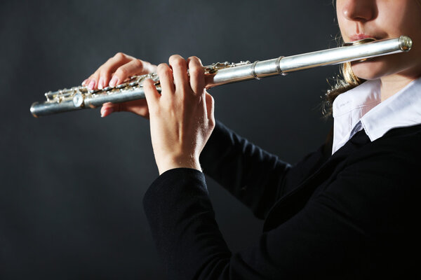 Музыкант играет на флейте на темном фоне

