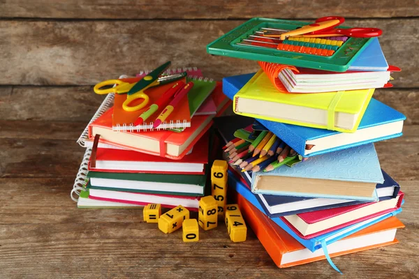 Stapel boeken en schrijfwaren op houten achtergrond — Stockfoto