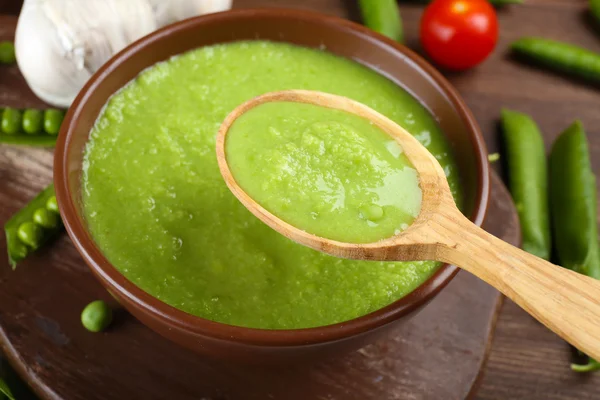 Tasty peas soup and vegetables on table close up — Stock Photo, Image