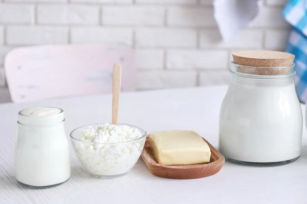 Mléčné výrobky na dřevěný stůl, na pozadí cihlová zeď — Stock fotografie