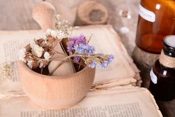 Παλιό βιβλίο με ξηρά λουλούδια στο Γουδί και μπουκάλια στο τραπέζι σε κοντινό πλάνο — Φωτογραφία Αρχείου