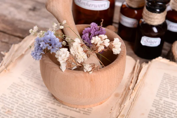 Livro velho com flores secas em argamassa e garrafas na mesa de perto — Fotografia de Stock