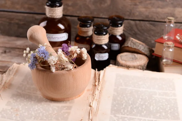 Livro velho com flores secas em argamassa e garrafas na mesa de perto — Fotografia de Stock