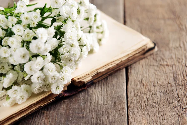 Livro velho com belas flores na mesa de madeira de perto — Fotografia de Stock