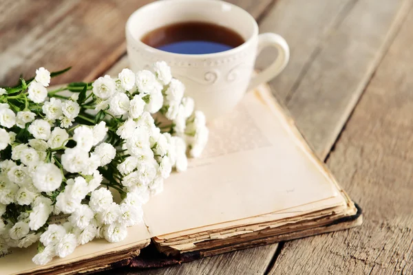 Libro viejo con hermosas flores y taza de té en la mesa de madera de cerca — Foto de Stock