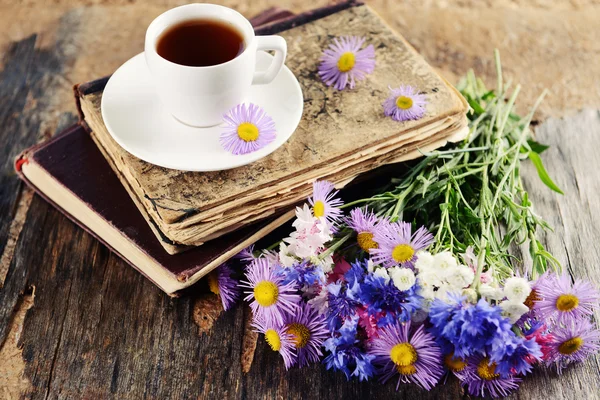 Libros antiguos con hermosas flores y taza de té en la mesa de madera de cerca —  Fotos de Stock